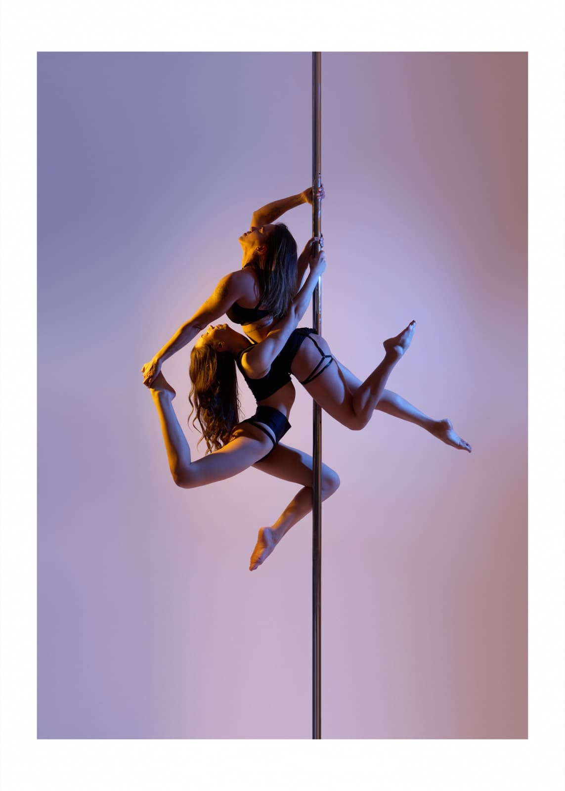 Duo pose at the pole in purple-rosé light